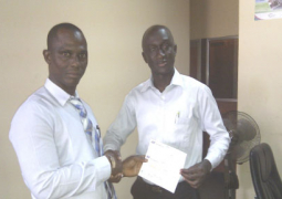 saikou bah left receiving cheque from a gamcel staff